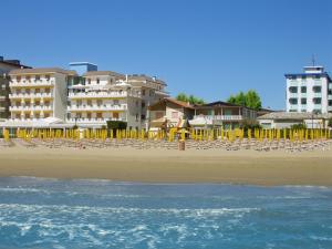 a beach with chairs and buildings and the ocean at Hotel Bellaria in Lido di Jesolo