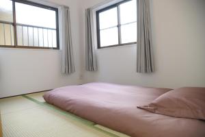 a bed in a room with two windows at Osaka Shinsaibashi Dotonbori Courtyard Villa in Osaka