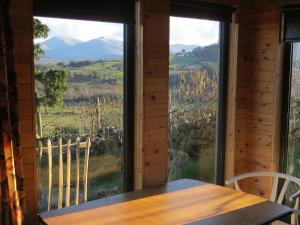 a table and chairs in a room with a large window at Panorama Peace Nature in Castlewellan