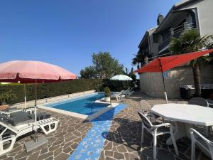 een patio met tafels en parasols en een zwembad bij Villa Bregi with Swimming Pool in Matulji