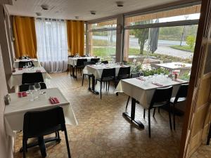 un restaurant avec des tables blanches, des chaises et des fenêtres dans l'établissement Comme chez soi, à Jas