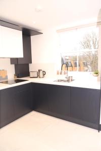 una cocina con armarios negros y fregadero en Star London Edgware Road 2-Bed Haven, en Londres