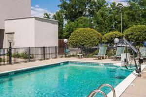 a swimming pool with blue chairs next to a fence at Travel Inn-Flowood in Flowood