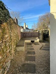 a stone wall with a bench next to a building at Bright and sunny village home in Ipplepen