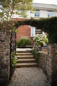 a brick house with a gate and stairs in front at Bright and sunny village home in Ipplepen