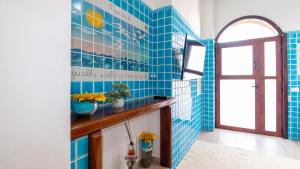 a blue tiled bathroom with a sink and a window at Appartamento il Maestrale Casa Vacanza in Càbras +26 photos