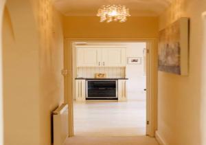 una cocina con armarios blancos y una lámpara de araña en Perfect Cotswold Home with vast stunning Ground's, en Painswick