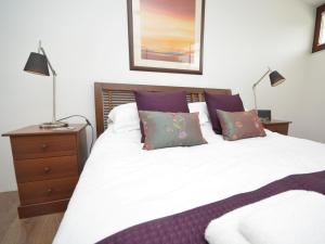 a bedroom with a white bed with purple pillows at 1 bed in Westward Ho 61767 in Westward Ho