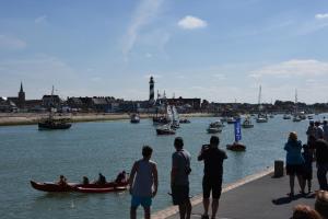 a group of people standing on a pier looking at boats in the water at Gîte sur Grand Fort Philippe in Grand-Fort-Philippe