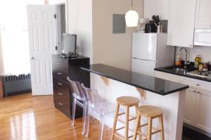 a kitchen with a black counter top and stools at Midtown Nest Studio Self Serviced Apartment Sleeps 5 in New York