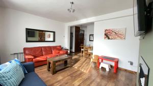 a living room with a red couch and a table at 2 Bedrooms 2 Stations in London