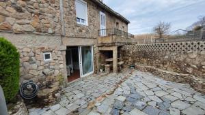 A Leiriña - Casa rural para desconexión في La Cañiza: مبنى حجري مع فناء وجدار حجري