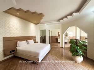 a bedroom with a large bed and a bathroom at Drops Motel Araraquara in Araraquara