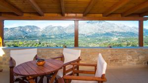 una mesa y sillas en un balcón con montañas en villa Morfeas en Dhamavólos