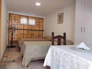 Zimmer mit 2 Betten, einem Tisch und einem Stuhl in der Unterkunft MELMAR - Habitación triple con baño privado in Godoy Cruz