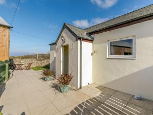 a small white house with a patio with potted plants at 1 Bed in Sennen CLOPC in St Just