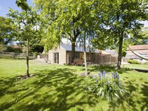 a yard with trees and blue flowers in front of a house at 1 Bed in Masham G0089 in Thornton Watlass