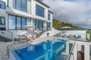 a house with a swimming pool and patio furniture at A balcony over Funchal and sea Monte White House in Funchal