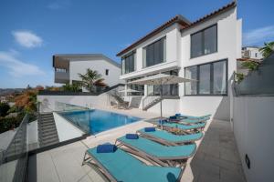a villa with a swimming pool and lounge chairs at A balcony over Funchal and sea Monte White House in Funchal