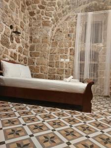 a bed in a room with a brick wall at Hebi house in ‘Akko