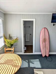 a pink surfboard leaning against a wall next to a table at Tower Circle Motel in Buxton