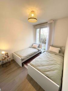2 camas en una habitación con ventana en Appartement 65m2 avec terrasse privé & jacuzzi, en Vaulx-en-Velin