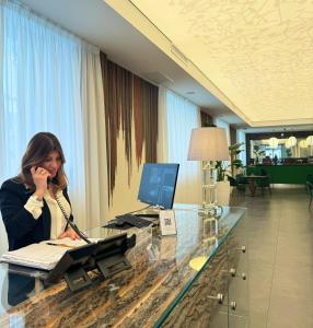 une femme assise à un bureau et parlant au téléphone dans l'établissement Outside Boutique Hotel, à Foggia