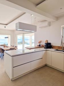 eine Küche mit weißen Schränken und einem Esstisch in der Unterkunft Villa Maritima-Meerblick-Infinity Pool-Luxus-Relax in Poljane