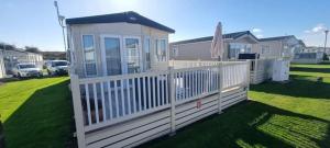a house with a white fence in a yard at Seasalter Cosy Caravan, in Seasalter