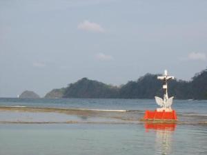 a red boat with a cross in the water at Cabaña La Punta in Colón