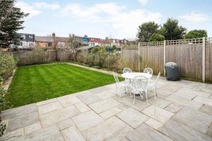 a patio with a table and chairs in a backyard at Contemporary 5 Bedroom with Garden North Finchley in London