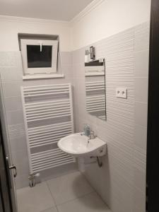 a white bathroom with a sink and a tv at Apartman Silver in Zádiel