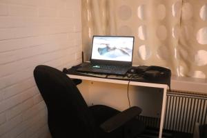 a laptop computer sitting on a desk with a chair at Cozy one room apartment in Herlev
