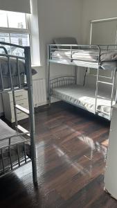 a room with three bunk beds and a wooden floor at Sarsfield Hostel in Dublin