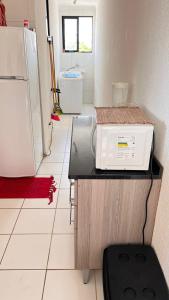 a kitchen with a refrigerator and a counter with a microwave at Apartamento com vista para o mar in Conde