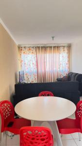 a living room with a white table and red chairs at Apartamento com vista para o mar in Conde