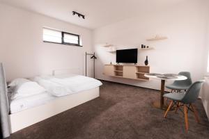 a bedroom with a bed and a table and a tv at Zenstay ApartHotel in Topliţa