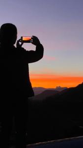 a person taking a picture of the sunset at Allotjaments rurals Can Punti in Vallfogona de Ripolles