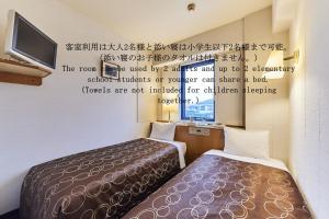 a room with two beds and a tv and writing on the wall at Urayasu Sun Hotel in Urayasu