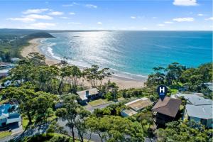 an aerial view of a beach with houses and the ocean at Sapphire Views - Narrawallee Beach in Narrawallee