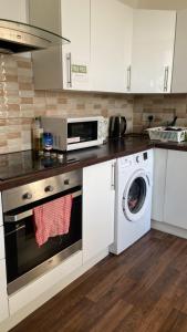 a kitchen with a washing machine and a microwave at Sarsfield Hostel in Dublin