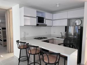 een keuken met witte kasten en een aanrecht met krukken bij Hermoso Apartamento moderno y vacacional in Ricaurte