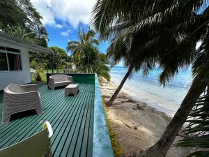 Fitii的住宿－Exclusive Beach & Calm at Vaiora House，海滩旁带绿色甲板的房子
