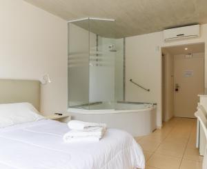 ein Schlafzimmer mit einer Badewanne und einem Bett mit Handtüchern in der Unterkunft Villa Agostina Apart & Spa in Mar de las Pampas