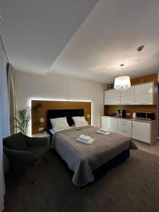 a bedroom with a bed and a chair and a kitchen at NCM Apartments Seaside Park in Kołobrzeg