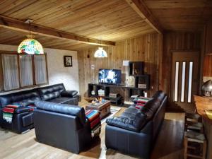 uma sala de estar com sofás de couro preto e uma televisão em Hermosa cabaña vista al bosque em La Marquesa