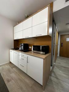 cocina con armarios blancos y microondas en NCM Apartments Seaside Park en Kołobrzeg