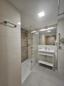 een badkamer met een glazen douche en een wastafel bij NCM Apartments Seaside Park in Kołobrzeg