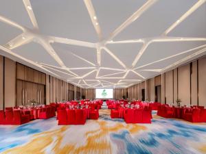 um grande salão de banquetes com cadeiras vermelhas e um ecrã em Holiday Inn Chengdu East, an IHG Hotel em Chengdu