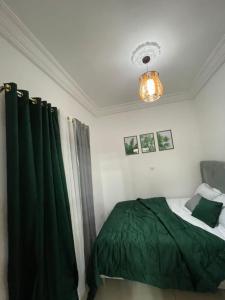 Un dormitorio con una cama verde y una lámpara de araña. en Superbe appartement meublé en résidence LBV en Libreville